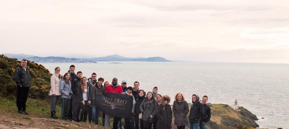 一群出国留学的欧大学生站在大海前，举着欧大的横幅